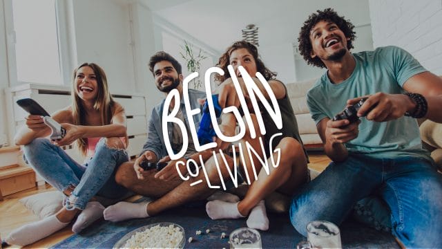 Cuatro amigos felices jugando video juegos con el logo de Begin CoLiving en el frente
