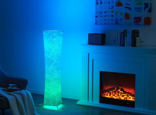 Accesorio de piso para iluminación LED colorida en sala de piso de madera frente a chimenea artificial